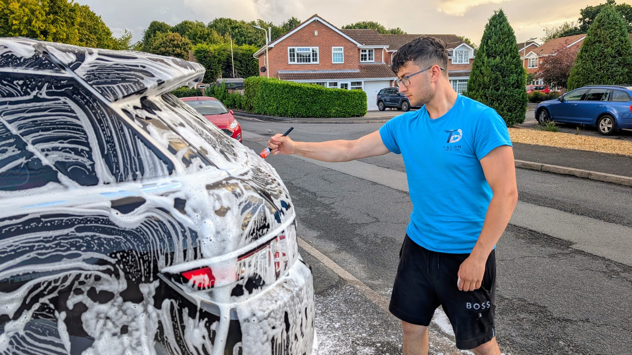 Talon carefully detailing a black SUV with a soft brush during prewash